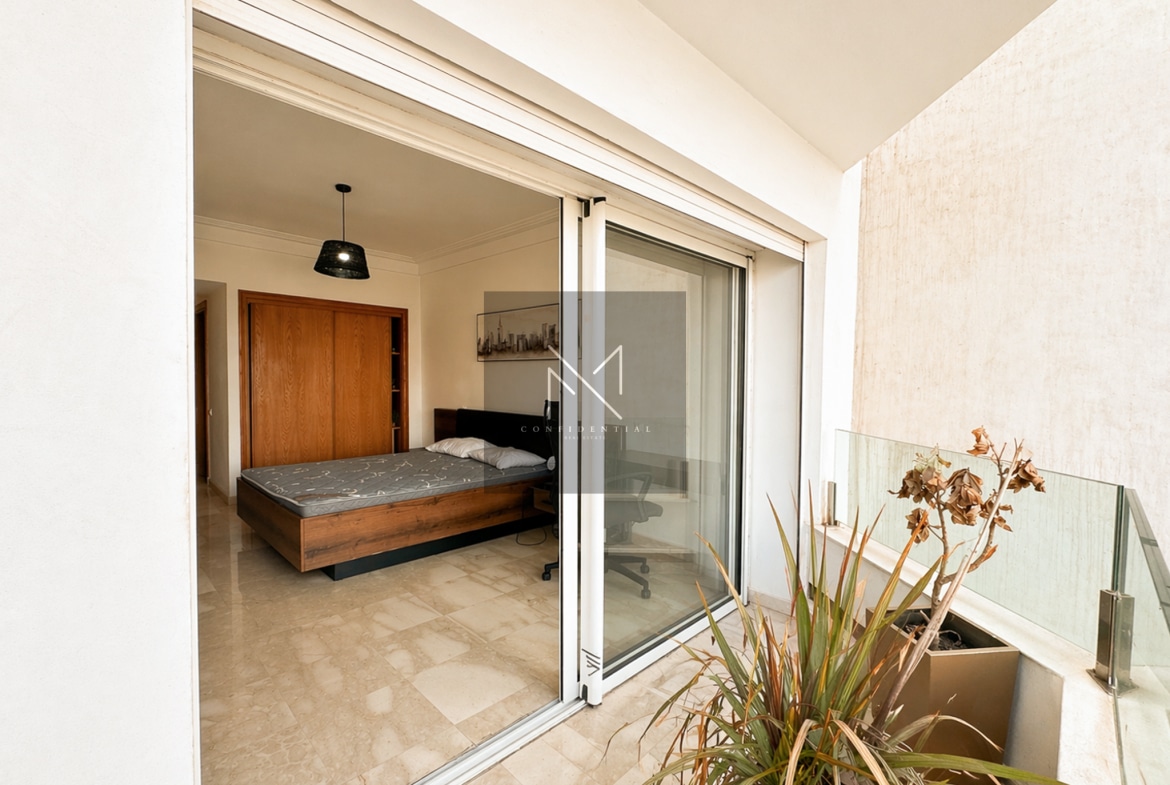 Chambre suite parentale avec lit en bois, balcon privé, luminosité naturelle – Résidence Casablanca